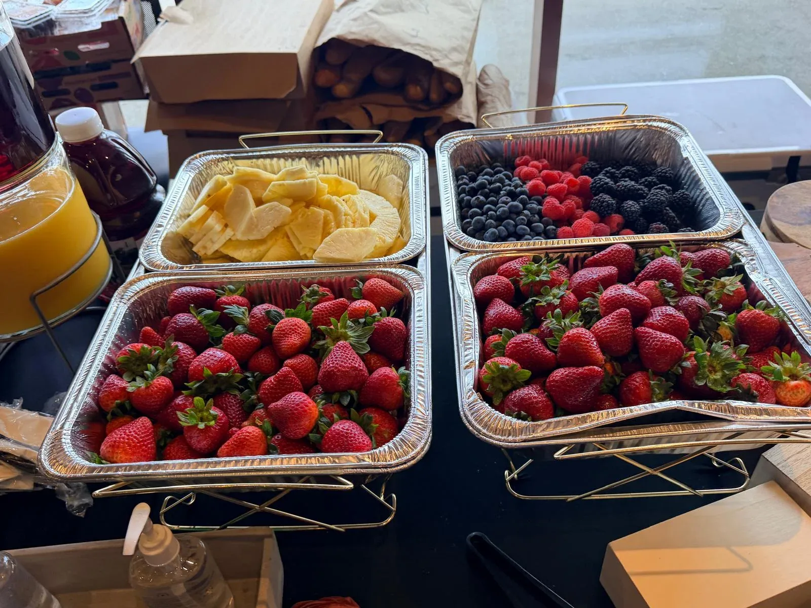 Chilled display of fresh strawberries, blackberries, blueberries, and sliced pineapple alongside chilled juices