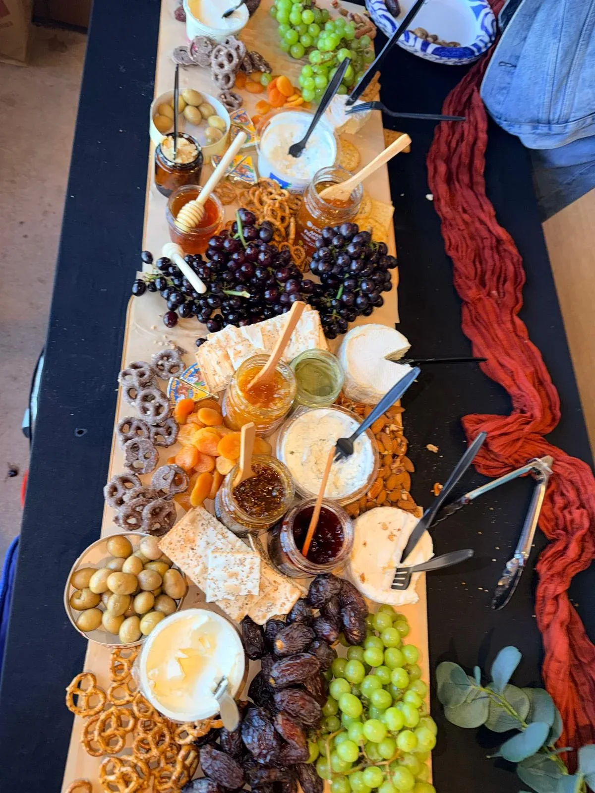 Detailed view of Mediterranean grazing board with Brie, honey with wooden dipper, fig preserves, olives, dates, and crackers