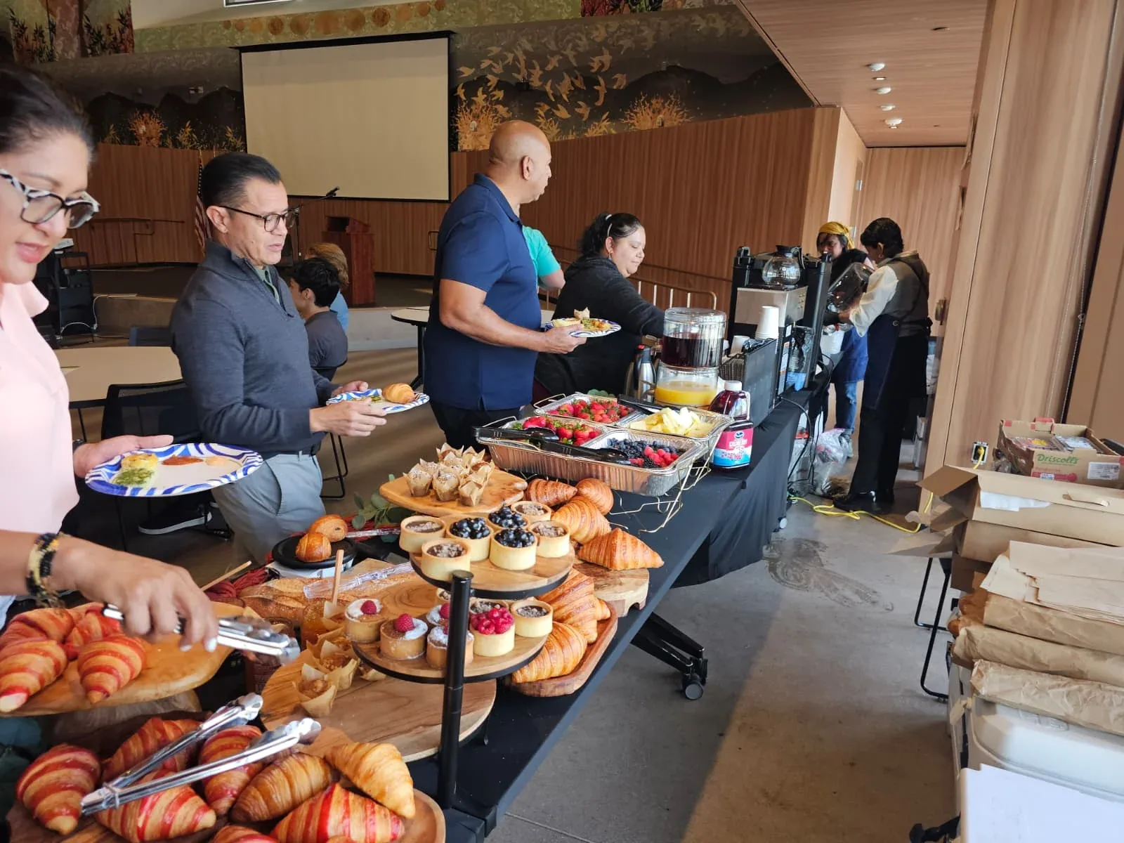 LA County public defenders and attorneys seated in auditorium with stage, American flag, and breakfast buffet during seminar