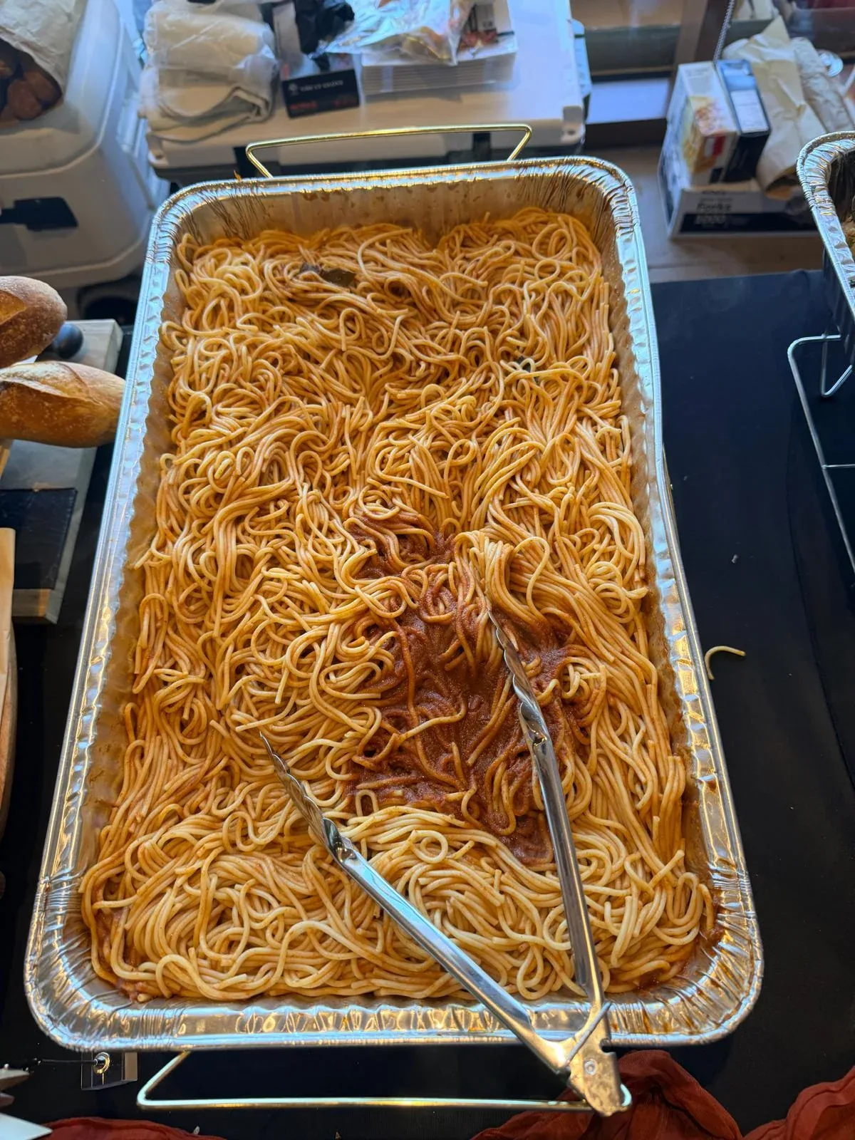 Al dente spaghetti tossed in rich house marinara sauce in full-size catering pan with tongs