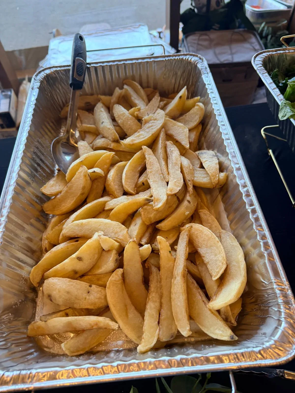 Crisp seasoned Yukon gold potato wedges in catering steam table pan for hot lunch buffet
